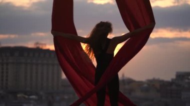 Kadın dansçının silueti esnekliğini gösteriyor ve yavaş çekimde dramatik bir gökyüzü sırasında şehrin arka planında kırmızı havadan ipekle ayrılıyor. Tutku, arzu ve cazibe kavramı 