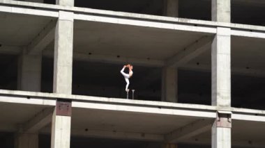 Esnek kadın sirk sanatçısı terk edilmiş binada yaya olarak dengesini koruyor. Bükülme ve denge kavramı 