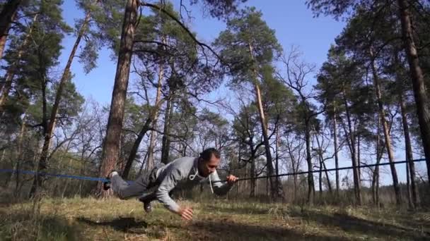 Hombre saltando y haciendo trucos en slackline en el bosque en cámara lenta — Vídeos de Stock