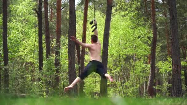 Circus artist doing calisthenics in the green park with aerial straps. — Stock Video