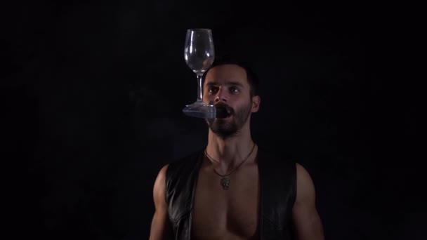 En man håller en kniv i munnen, kastar och håller sitt glas i balans. Unik cirkusfärdighet. — Stockvideo