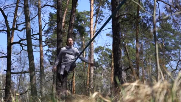Uomo che salta e fa trucchi su slackline nella foresta al rallentatore — Video Stock