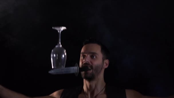 Un homme tient un couteau dans sa bouche, jetant et gardant son verre en équilibre. Compétence unique en cirque. — Video