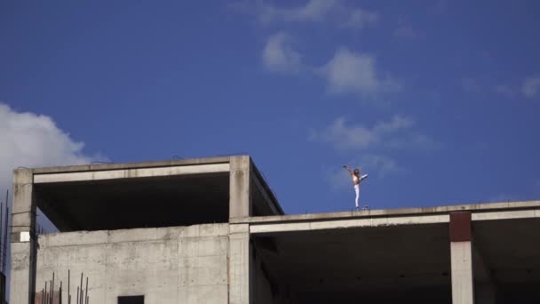 Mujer flexible de pie en el borde del edificio en construcción. Concepto de libertad, coraje y fuerza de voluntad — Vídeos de Stock