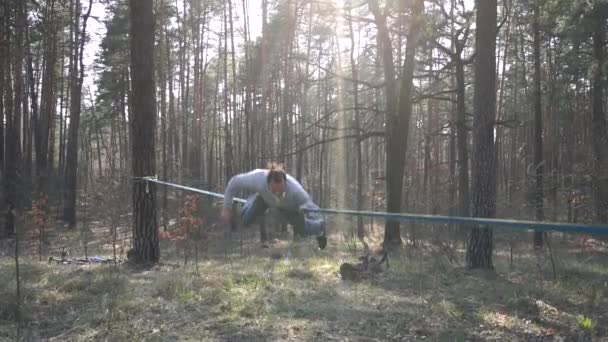 Man springen en doen trucs op slackline in het bos in slow motion — Stockvideo