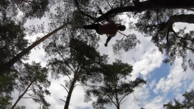 Adam yeşil parkta TRX veya hava kayışlarıyla jimnastik yapıyor. Sağlıklı yaşam tarzı ve sağlık