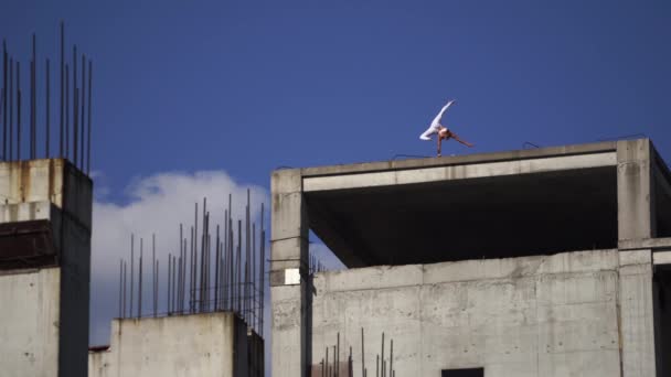 Flexibele vrouwelijke circusartiest houdt aan de ene kant balans aan de rand van het gebouw in aanbouw. Motivatie, passie en prestatieconcept — Stockvideo