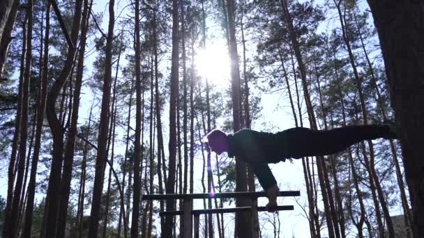 Homem fazendo ginástica nas barras paralelas na floresta. Estilo de vida saudável — Vídeo de Stock