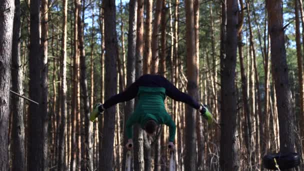 Homem fazendo ginástica nas barras paralelas na floresta. Estilo de vida saudável — Vídeo de Stock