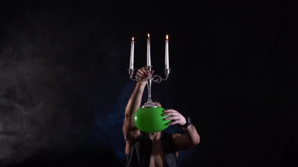 Circus artist holding knife in the mouth blow up balloon with candelabrum on it and catch it keeping in balance — Stock Video