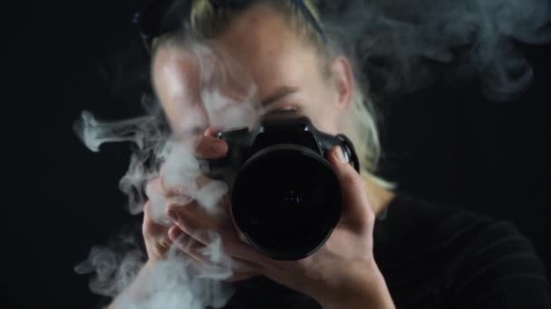 Молодий чоловік з професійною камерою з димом йде зсередини — стокове відео