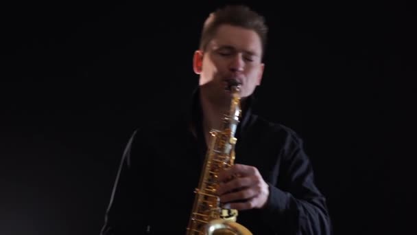 Knappe man spelen op saxofoon geïsoleerd op zwarte achtergrond — Stockvideo