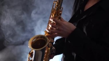 Tütsülenmiş arka planda izole edilmiş saksafonda çalan ellerin yakınlaşması 