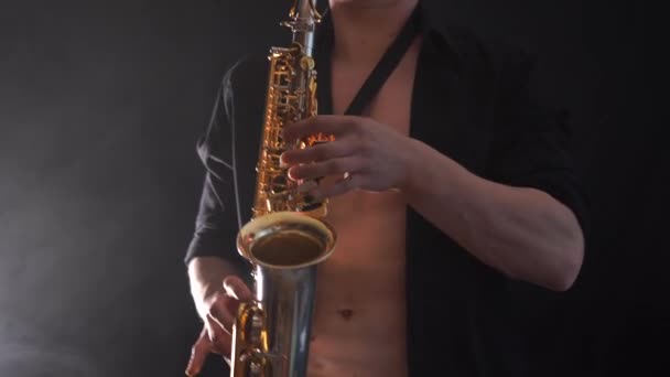 Man bär svart skjorta spela på saxofon isolerad på rökt bakgrund — Stockvideo