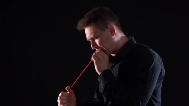 Man cant inflate long balloon by his length isolated on black background — Stock Video