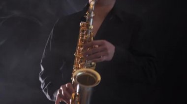 Tütsülenmiş arka planda izole edilmiş saksafonda çalan ellerin yakınlaşması 