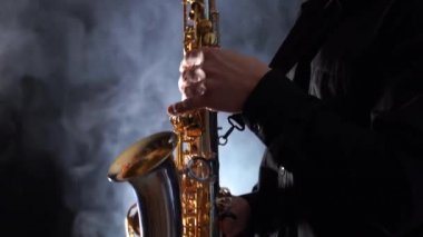 Tütsülenmiş arka planda izole edilmiş saksafonda çalan ellerin yakınlaşması 
