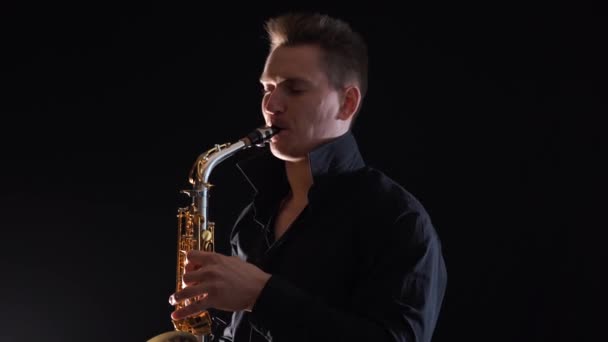 Snygg man spelar på saxofon isolerad på svart bakgrund — Stockvideo