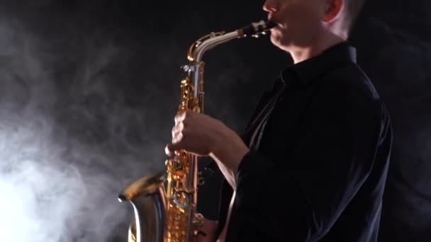 Man wearing black shirt playing on saxophone isolated on smoked background — Stock Video