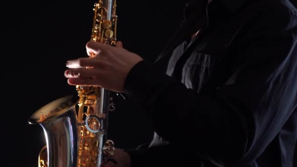 검은 배경에서 고립된 색소폰으로 연주하는 손을 클로즈업 — 비디오