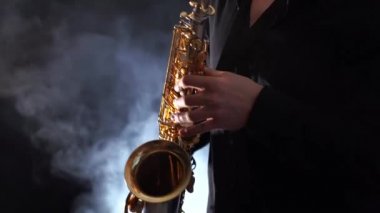 Tütsülenmiş arka planda izole edilmiş saksafonda çalan ellerin yakınlaşması 