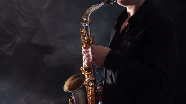 Крупный план рук, играющих на саксофоне, изолированных на копченом фоне — стоковое видео
