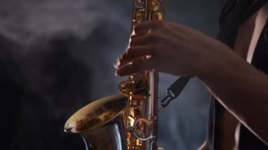 Tütsülenmiş arka planda izole edilmiş saksafonda çalan ellerin yakınlaşması 