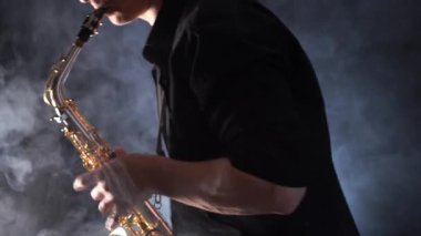 Tütsülenmiş arka planda izole edilmiş saksafonda çalan ellerin yakınlaşması 