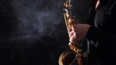 Saksafonda çalan yakışıklı adam siyah arka planda izole edilmiş. 