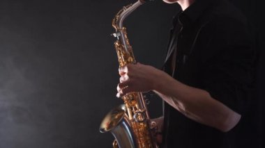 Tütsülenmiş arka planda izole edilmiş saksafonda çalan ellerin yakınlaşması 