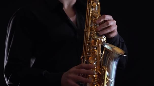 Närbild av händer spelar på saxofon isolerad på svart bakgrund — Stockvideo
