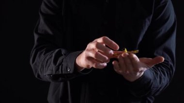 Ellerinin yakınlığı elindeki sihirli bebeği kontrol ediyor. Siyah arka planda yükseliyor.