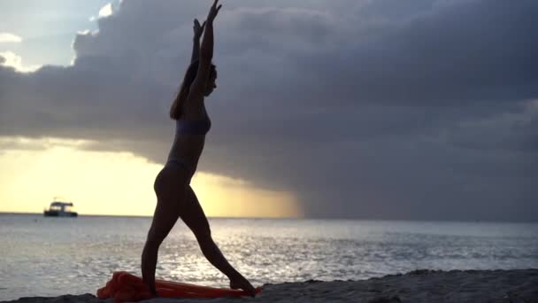 Silhouet van flexibele pasvorm vrouw doen handstand met zijde tijdens dramatische zonsondergang met stormachtige wolken op de zeegezicht achtergrond. Concept van geluk, vrijheid en zorgeloosheid. — Stockvideo