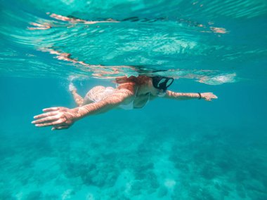 Suyun altında yüzen kadın. Tatiller, şnorkelle yüzme ve doğa kavramları. Su altı kamerasıyla çekilmiş.