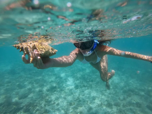 Mulher fazendo snorkeling com máscara subaquática com concha. Conceito de estilo de vida saudável e lazer. Tiro tirado com câmera subaquática — Fotografia de Stock