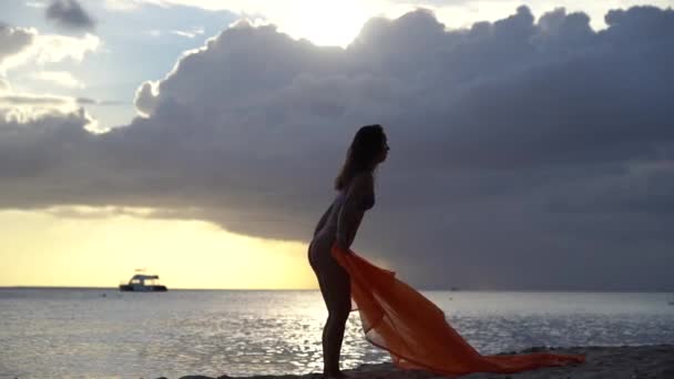 Mujer flexible en forma saltando con seda durante el dramático atardecer con nubes tormentosas. Concepto de individualidad, creatividad y confianza en sí mismo — Vídeo de stock