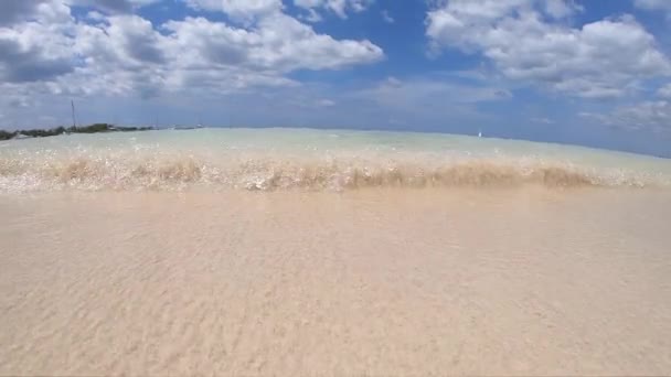 波は青い空と遅い動き、結晶、澄んだ水の白い雲の背景を持つ美しい熱帯のビーチに来ます。夏休み・休日のコンセプト. — ストック動画