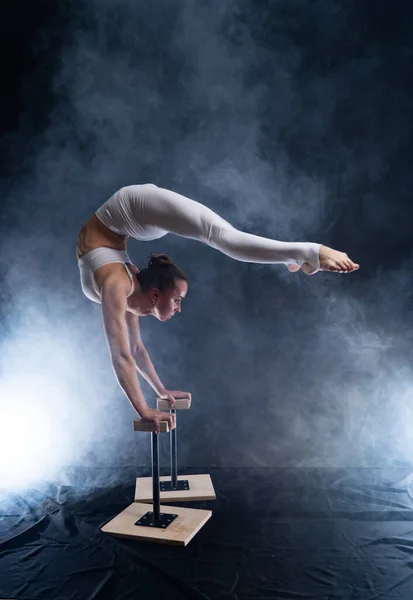Flexibel cirkusartist - kvinnlig akrobat gör handstand på baksidan och rökare bakgrund — Stockfoto