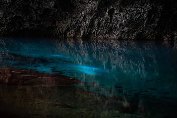 La luz desciende a la oscuridad de una caverna sumergida con un lago azul. Concepto de viaje y aventura. — Foto de Stock