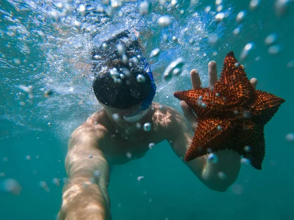 Чоловік тримає морську зірку під водою. Концепція подорожей та пригод — стокове фото