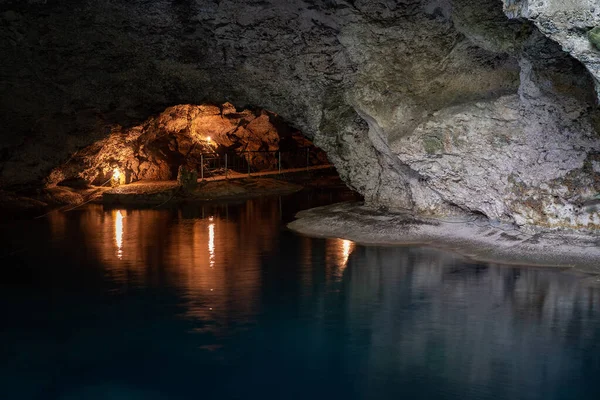 La luz desciende a la oscuridad de una caverna sumergida con un lago azul. Concepto de viaje y aventura. — Foto de Stock