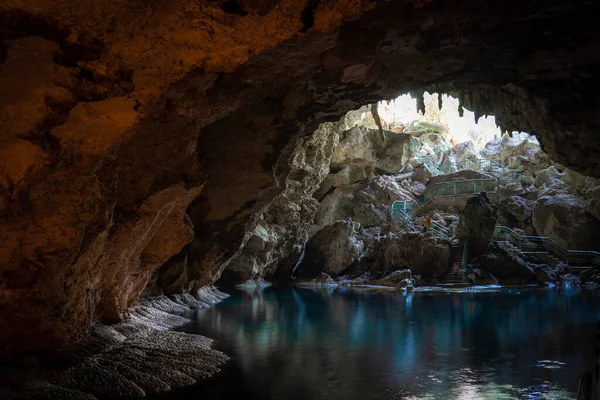 La luz desciende a la oscuridad de una caverna sumergida con un lago azul. Concepto de viaje y aventura. — Foto de Stock