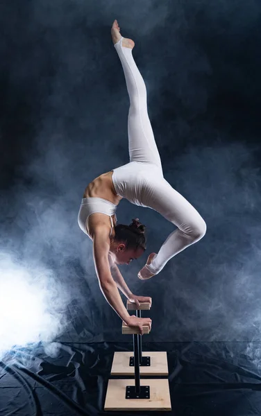 Flexibele circus artiest - vrouwelijke acrobaat doen handstand op de rug en roker achtergrond — Stockfoto