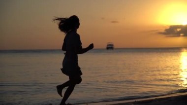Gün batımında kumsalda tek başına koşan kadın ağır çekimde. Keyif tatili kavramı bir tatil 