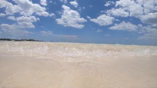 Vlna přijít a cákat na krásné tropické pláži s modrou oblohou a bílým mrakem pozadí ve zpomaleném filmu. Letní dovolená a přírodní prostředí koncept — Stock video