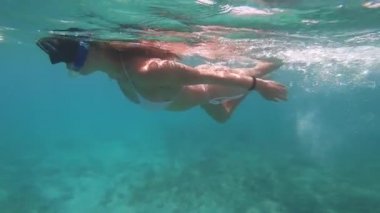 Suyun altında yüzen kadın. Tatil ve doğa kavramları. Su altı kamerasıyla çekilmiş.