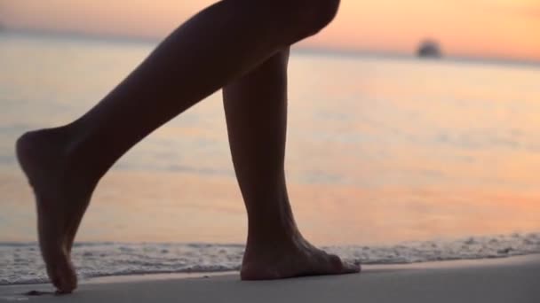 Großaufnahme von Frauenfüßen in Kleidern, die während des Sonnenuntergangs in Zeitlupe allein am Strand spazieren gehen. Konzept von Tourismus und Ruhe — Stockvideo