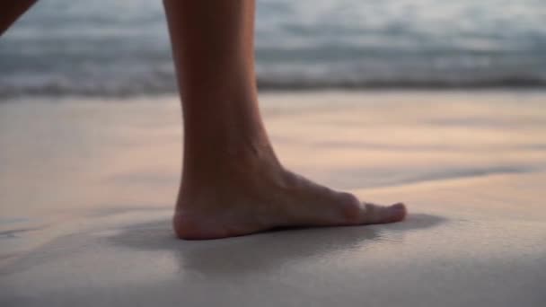 Lähikuva naisten jalat mekko kävelee yksin rannalla auringonlaskun aikana hidastettuna. Käsite loma ja rentoutua — kuvapankkivideo