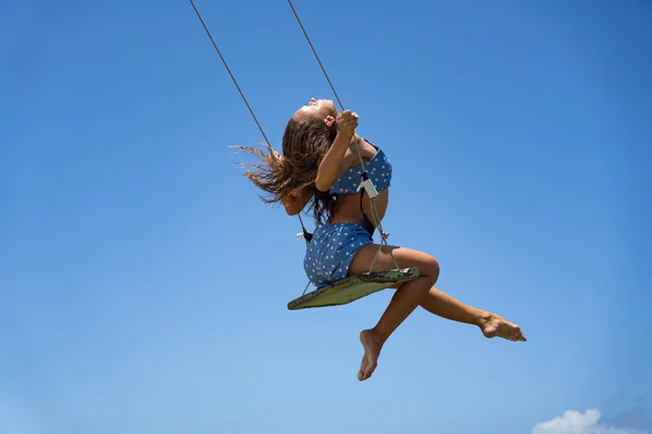 Giovane donna sull'altalena corda con sfondo cielo blu. Concetto di individualità, creatività — Foto Stock