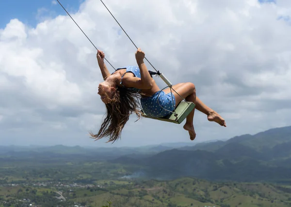 Mujer joven en el columpio cuerda con el cielo y las montañas de fondo. Concepto de libertad y felicidad — Foto de Stock